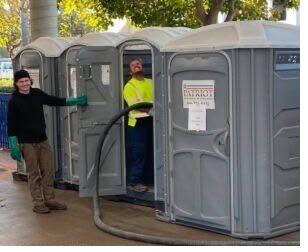 Technicians servicing a row of portable restroom units on site