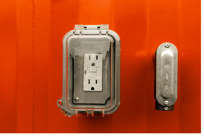 Weatherproof electrical outlet hardware on a jobsite restroom unit